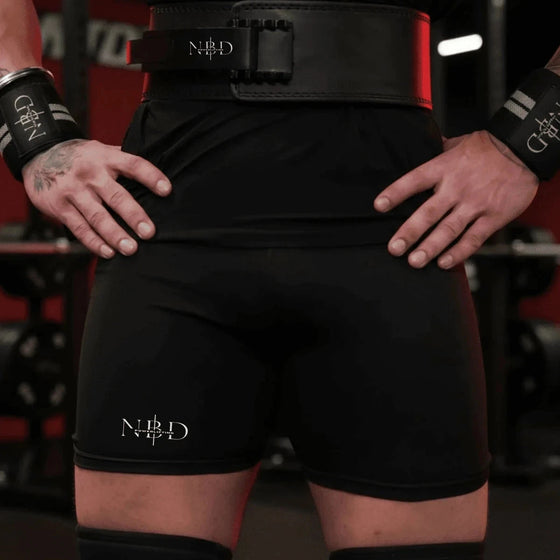 NBD training tights worn with a black lever belt and wrist wraps, NBD logo on the left thigh