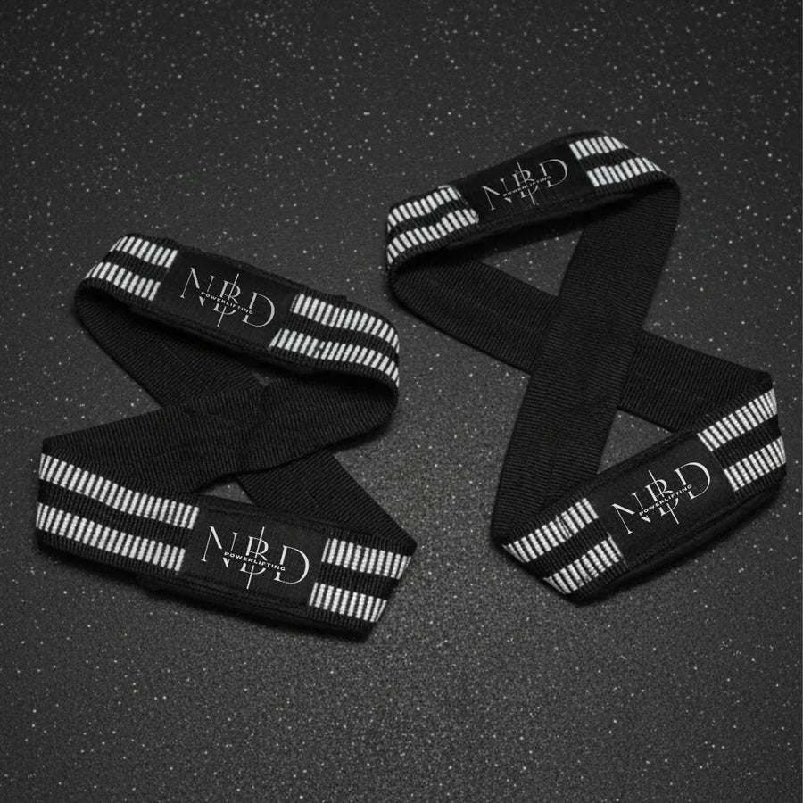 Pair of NBD figure-8 lifting straps with white rubber striping and the NBD logo on a gym floor