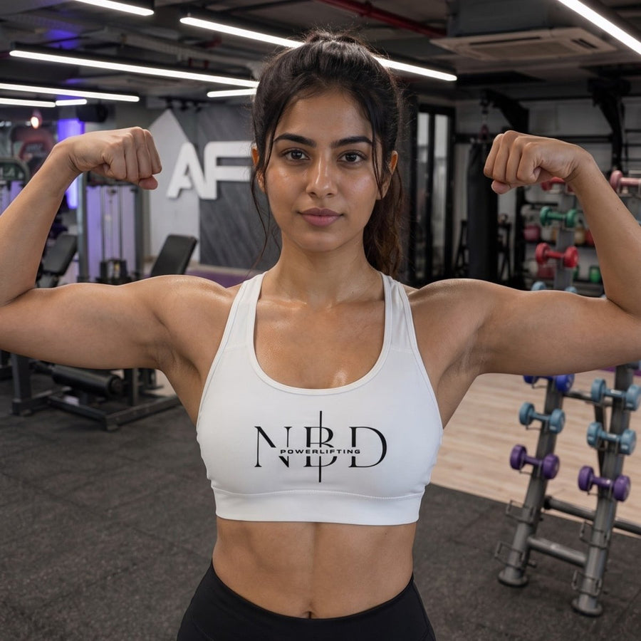 NBD high-performance sports bra - front view flexing biceps, white racerback gym wear for women