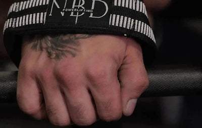 NBD lifting strap locked on a barbell, white rubber band on the wrist during a deadlift grip