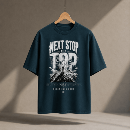 NBD 'Next Stop The Top' oversized T-shirt in petrol blue, hanging on a wooden hanger, front print of a lifter on a mountain summit with 'Never Back Down' below
