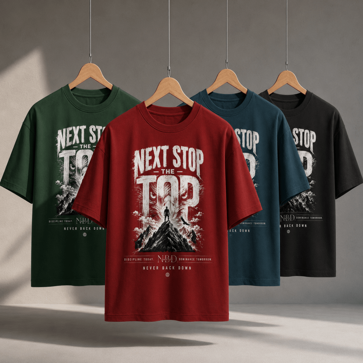 NBD 'Next Stop The Top' oversized T-shirt shown in all four colourways — bottle green, red, petrol blue and black — hanging side by side