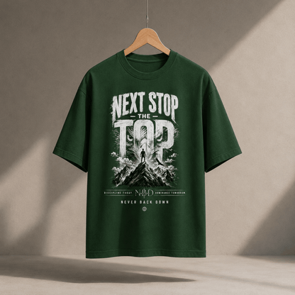 NBD 'Next Stop The Top' oversized T-shirt in bottle green, hanging on a wooden hanger, front print of a lifter on a mountain summit with 'Never Back Down' below
